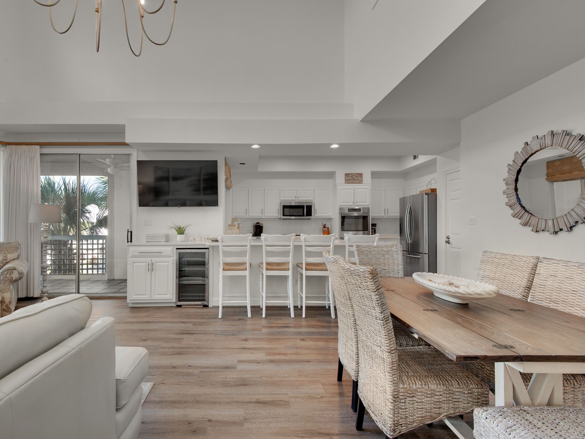 Cozinha moderna com armários brancos, uma ilha central e um espaço de refeições com cadeiras de vime.