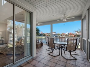 Un patio techado con una mesa y sillas, un ventilador de techo y vistas a una zona residencial.