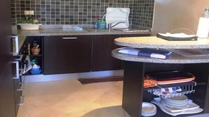 A kitchen with dark cabinets, a granite countertop, a built-in dishwasher, and a dish rack. - Beautiful apartment in River Palm 4397 (Marrakech)