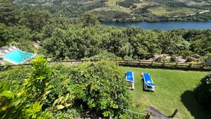Blick auf eine gebirgige Landschaft mit Pool und zwei Liegestühlen auf einer Wiese.