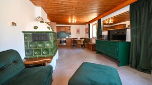 Una sala de estar con chimenea, sofá verde y un área de comedor con mesa y sillas.