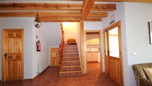 Eine Holztreppe führt zu einem Küchenbereich mit Fliesenboden und Holztüren.