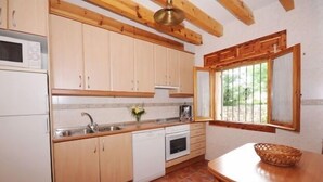 Eine Küche mit Holzausstattung, einem Geschirrspüler, einer Mikrowelle und einem Fenster mit Blick ins Grüne.