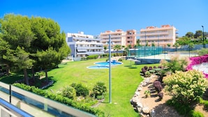 A hotel with multiple floors, a swimming pool, and a well-maintained garden with various plants and a fountain.