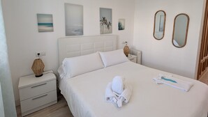 Quarto de hotel bem arrumado, com uma cama grande, mesa de cabeceira com abajur e espelhos fixados na parede.