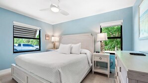Ein Schlafzimmer mit Bett, Nachttischen, einem Schreibtisch und einem Deckenventilator.
