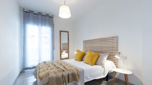 A bedroom with a bed, bedside table, lamp, and a window with curtains. - AirCon Apartment with Pool · Beach 100m · Parking · RUISEÑORES (Salou)