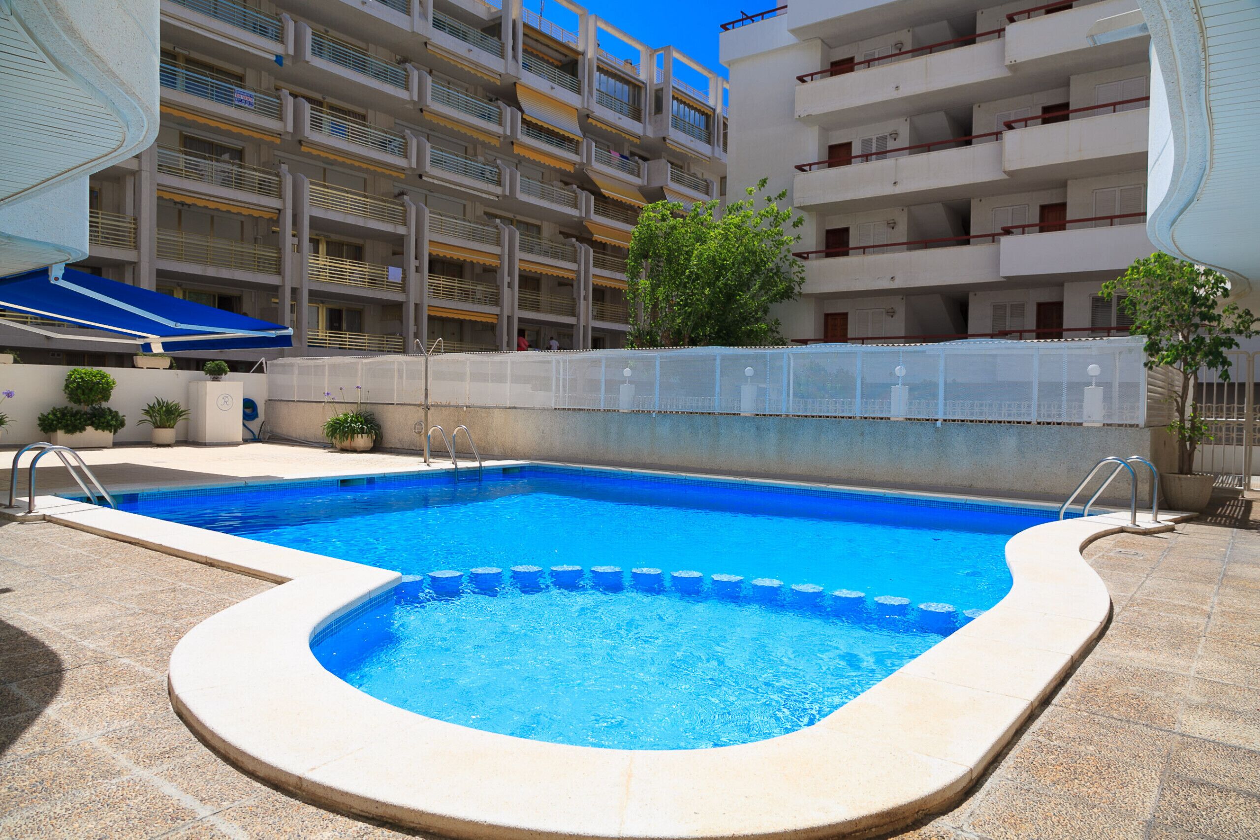 Una piscina de borde curvo, rodeada por una solana con azulejos.