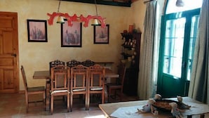 Un coin repas avec des chaises et une table en bois, un plafond en bois et une fenêtre avec des rideaux.