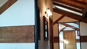Un couloir avec des poutres en bois au plafond et une porte en bois au fond.