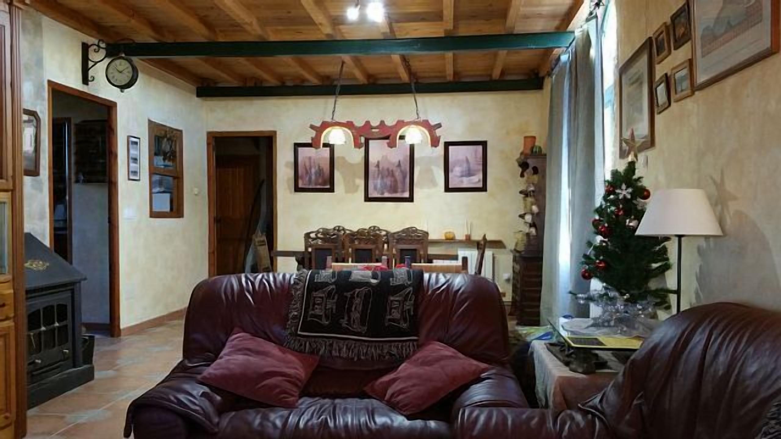 Un salon chaleureux avec un canapé en cuir, un plafond en bois et un sapin de Noël.