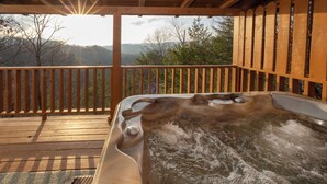 Un jacuzzi en una terraza de madera con vistas a montañas.