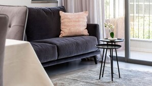 A modern living room with a dark grey sofa, a round side table, and a vase with a plant.