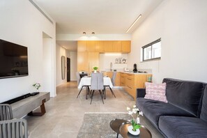 Un salon moderne avec un canapé foncé, une table basse et un téléviseur posé sur un meuble.