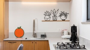 A modern kitchen with wooden cabinets, a stainless steel sink, a gas stove, and decorative wall art.