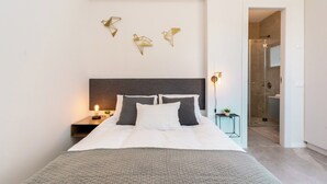 Un dormitorio moderno con una cama grande, una mesita de noche con lámpara, y un aplique de pared.