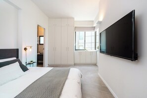 Une chambre à coucher moderne avec un lit, un téléviseur fixé au mur et un dressing.