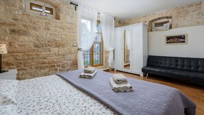 A bedroom with a stone wall, a bed with floral bedding, a black sofa, and a night sky mural. - Villa Casa Antignana with pool in Tinjan, Istria (Tinjan)
