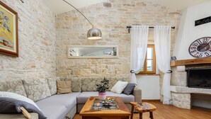 A cozy living room with a stone wall, a wooden coffee table, a sofa, and a fireplace. - Villa Casa Antignana with pool in Tinjan, Istria (Tinjan)