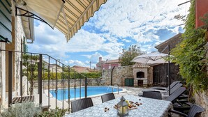 A poolside area with a table and chairs, a stone wall, and a view of a building in the background. - Villa Casa Antignana with pool in Tinjan, Istria (Tinjan)