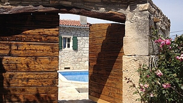 An open wooden door leading to a courtyard with a stone building in the background. - Villa Casa Antignana with pool in Tinjan, Istria (Tinjan)