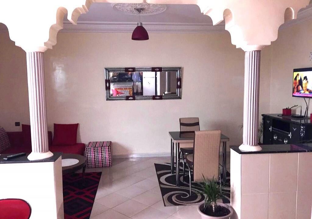 A hotel lobby with a dining area, a television, and a large mirror on the wall.