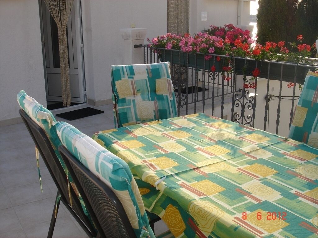 A balcony with a table and chairs, covered with a patterned tablecloth.