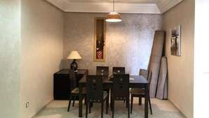 Un comedor con una mesa, sillas, una lámpara y un cuadro en la pared.