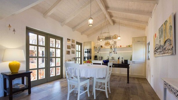 Une cuisine spacieuse avec un plancher en bois, un coin repas avec une table et des chaises, et une grande fenêtre offrant une belle vue.