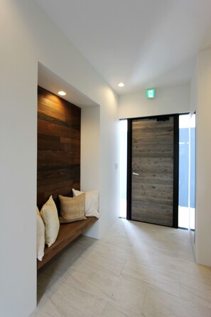 A hallway with a wooden bench and a large sliding door. - The Stella Hamahiga (Uruma)