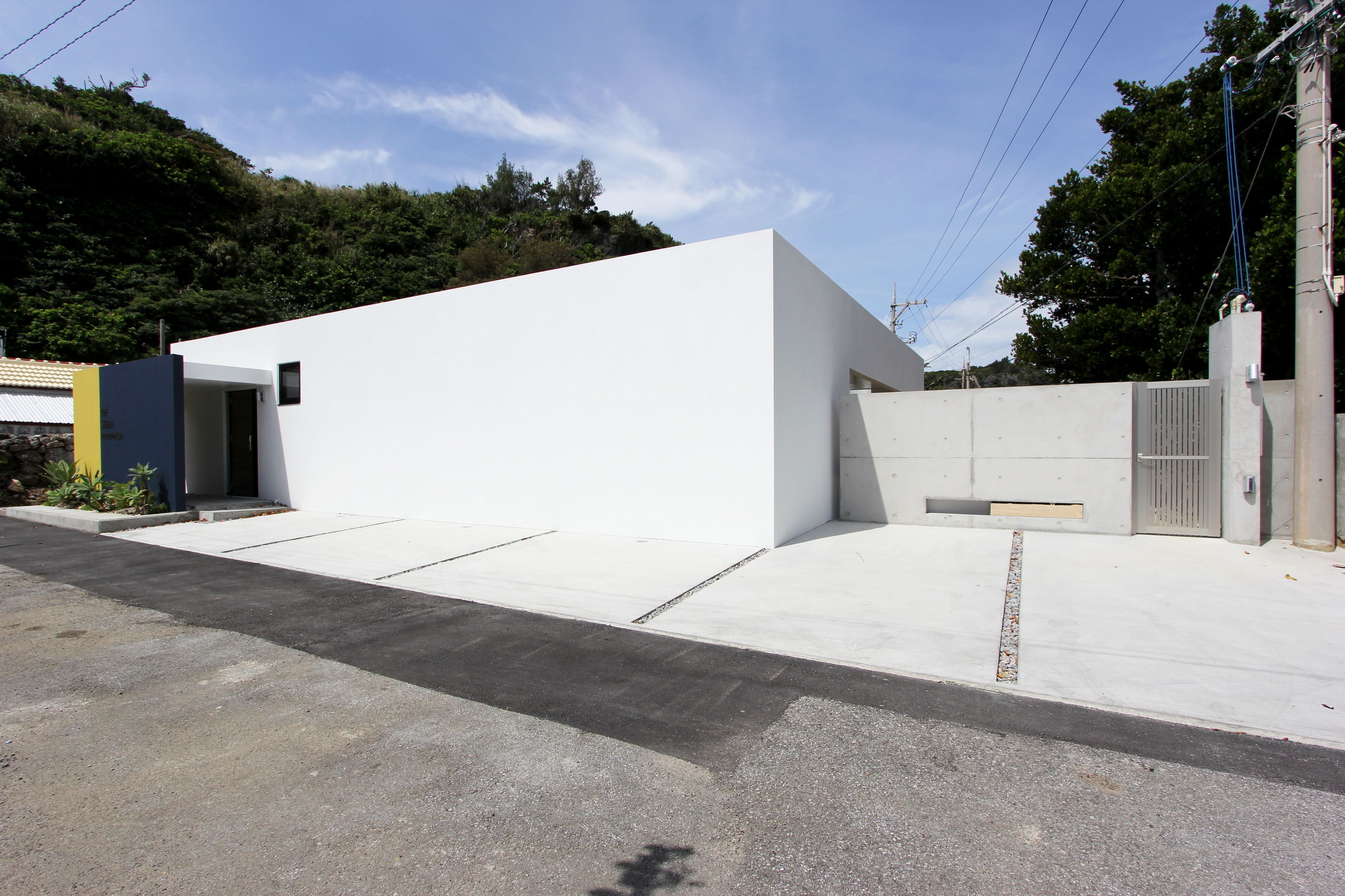 A modern building with a flat roof, a concrete entrance, and a small window.
