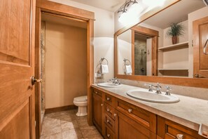 A bathroom with wooden cabinets, a double sink, and a large mirror. - Unit With/Private Balcony, Walk to Dining & Shops. (Keystone)