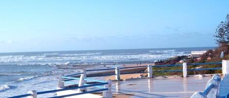 A coastal walkway with a railing, leading to the beach.