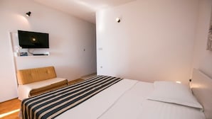 Une chambre d’hôtel moderne avec un grand lit, un téléviseur fixé au mur et un petit coin salon.
