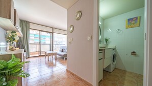 Un apartamento moderno con comedor, sala de estar con sofá, cocina con lavadora y balcón con vistas.