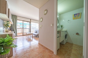 Um apartamento moderno com área de jantar, sala de estar com sofá, cozinha com máquina de lavar e varanda com vista.