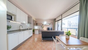 Una cocina moderna con armarios blancos, un microondas y un comedor con mesa y sillas.