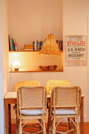 A dining area with wicker chairs, a hanging light fixture, and a wall-mounted sign with text.
