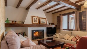A cozy living room with a fireplace, a sofa, a television, and a bookshelf. - Casa Rural El Abuelo Luis for 8 people (Molinicos)