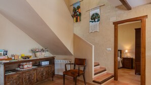 A staircase with wooden steps and a chair in a room with a rustic design, including a wooden cabinet and wall decorations. - Casa Rural El Abuelo Luis for 8 people (Molinicos)