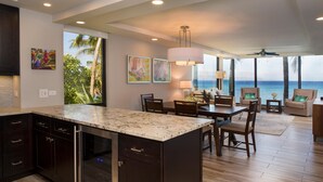 Cocina moderna con una isla grande, comedor con sillas y vista al océano.