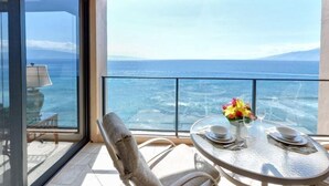 Un balcón con mesa lista para comer, con vistas a un cuerpo de agua y una montaña distante.