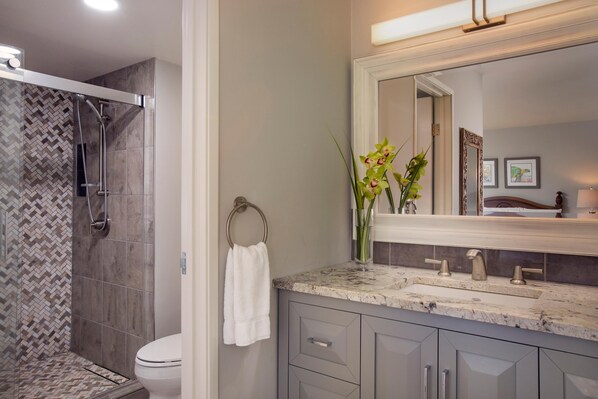 Une salle de bain équipée d’une douche, de toilettes, d’un lavabo et d’un grand miroir.