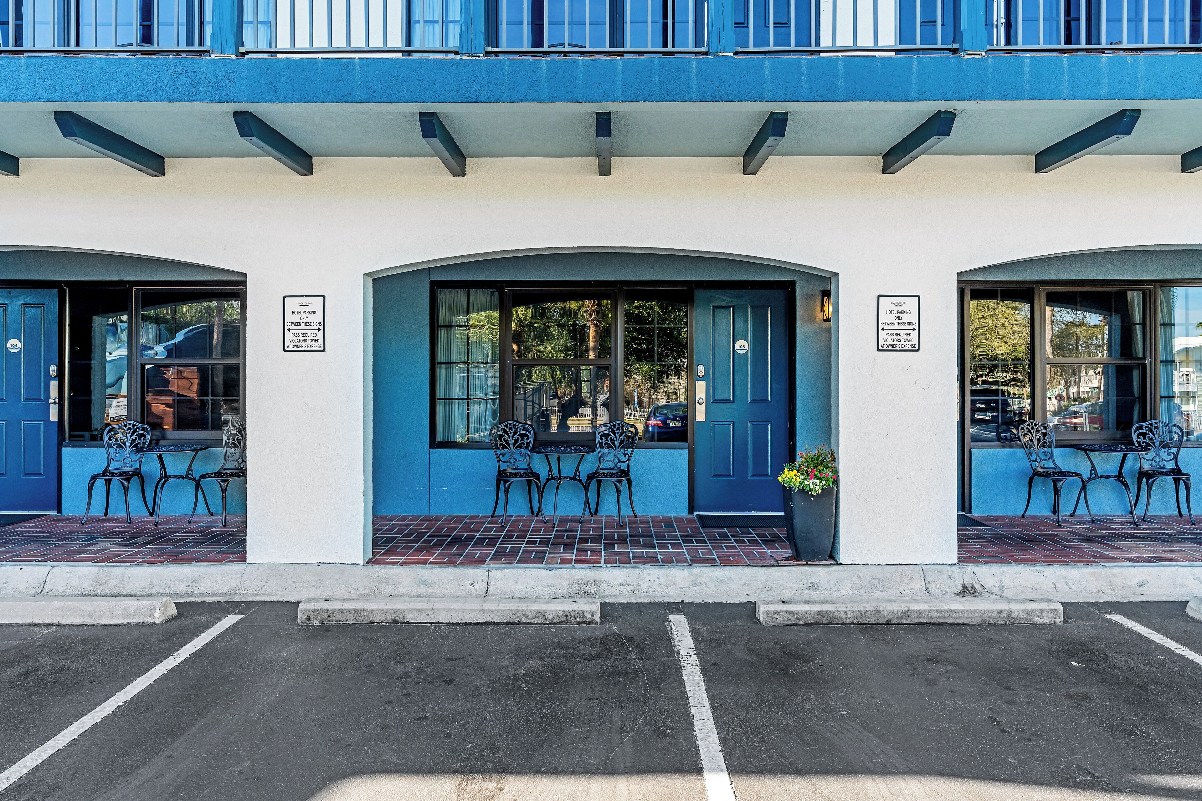 A building with a blue facade, two visible doors, and outdoor seating with chairs.