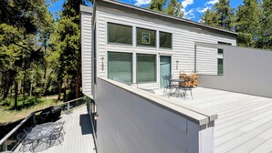 Ein modernes Haus mit Terrasse, großen Fenstern und einer Tür.