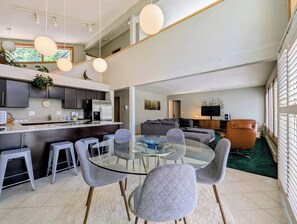 A modern kitchen with dark cabinets, a stainless steel refrigerator, and a round glass dining table with grey upholstered chairs. - Pet friendly, Private, Sauna, Free Shuttle (Keystone)