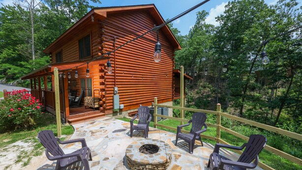 Eine Blockhütte mit einem Steinkamin und Adirondack-Stühlen.