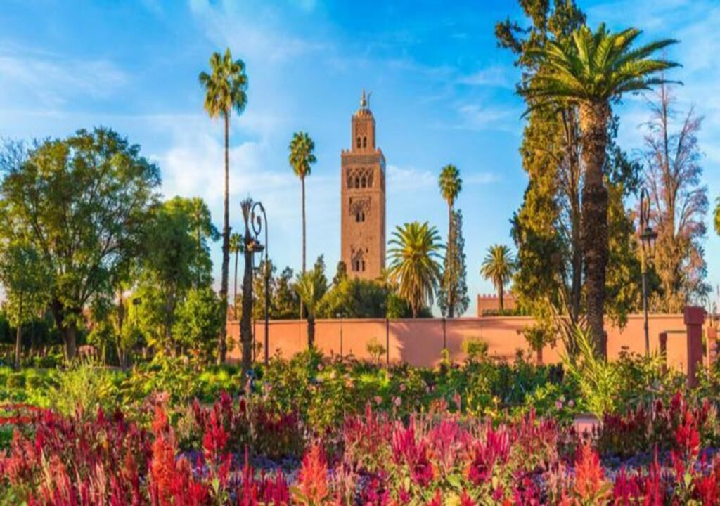 A historic tower with a clock, surrounded by lush greenery and palm trees.