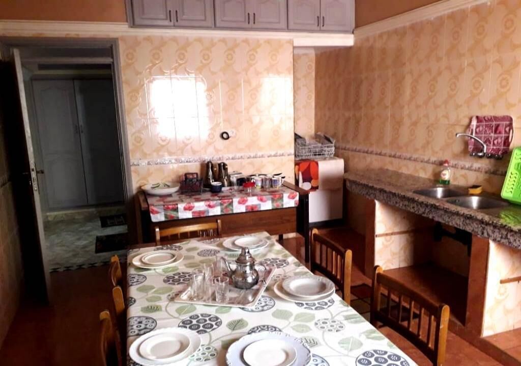 Une cuisine équipée d’une table à manger pour quatre personnes, d’un réfrigérateur et d’un évier.