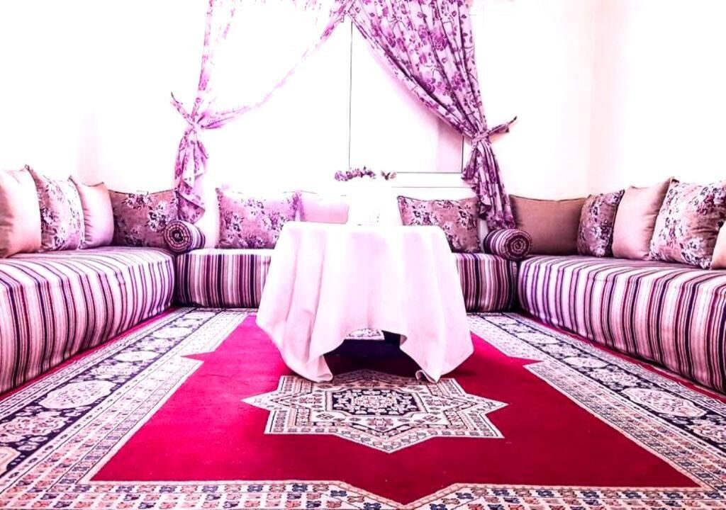 Une pièce avec une moquette rouge, un tapis à motifs et un canapé agrémenté de coussins à rayures.